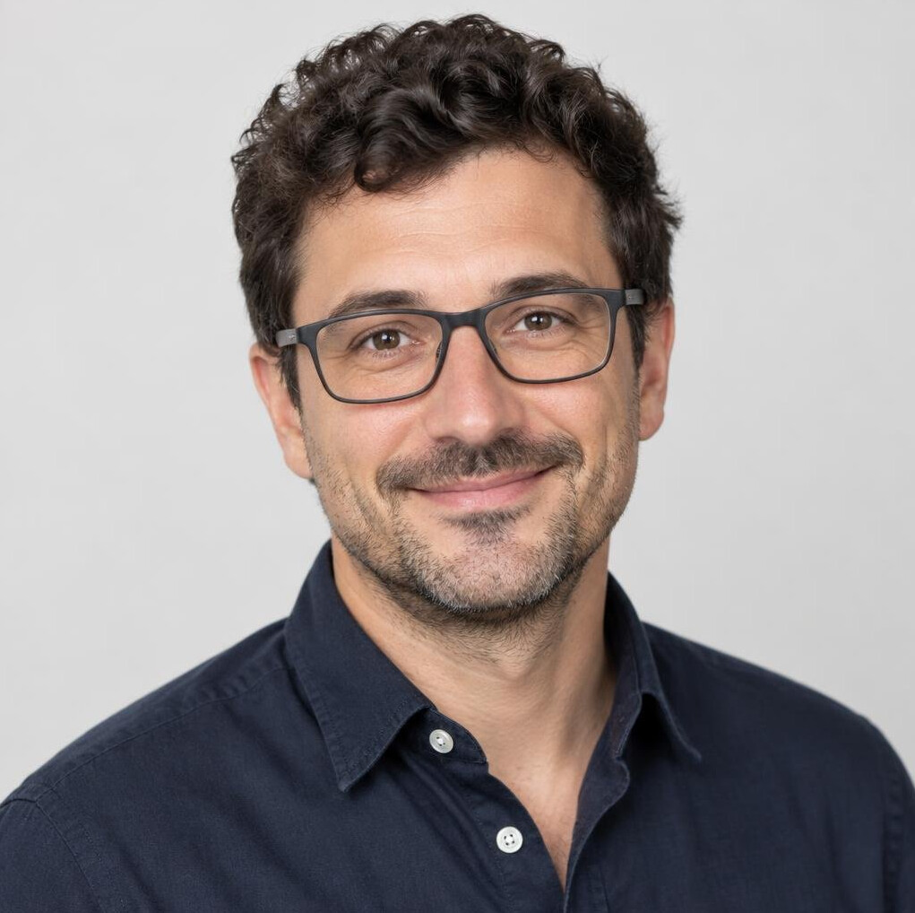 Portrait of a man with curly hair and glasses smiling